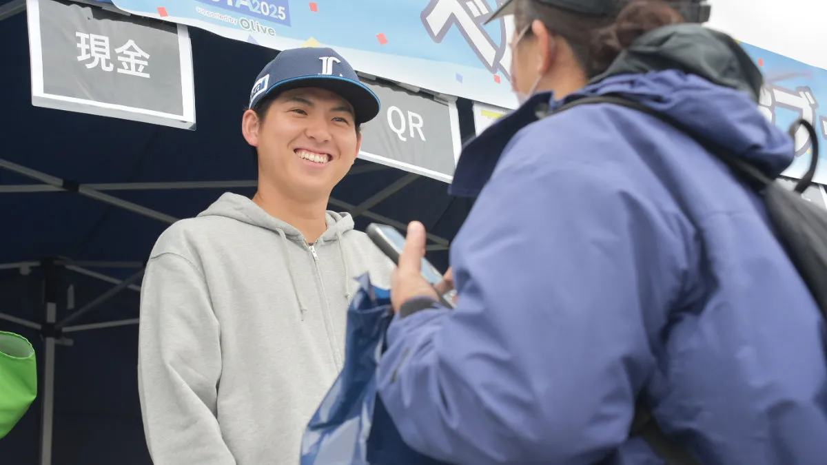 ベルーナのブースでファンに購入グッズを渡す武内夏暉投手【写真：著者撮影】