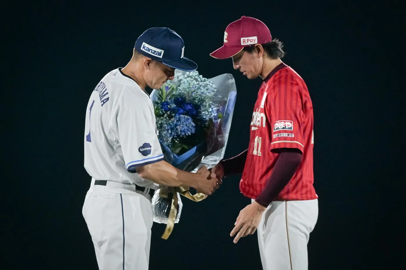 引退試合で栗山選手を抑え込んだ東北楽天・岸孝之投手から花束(写真右)。このあとのスピーチで栗山選手は「岸くん、ナイスボール。やっぱり良いピッチャーですね」と話した。©PLM