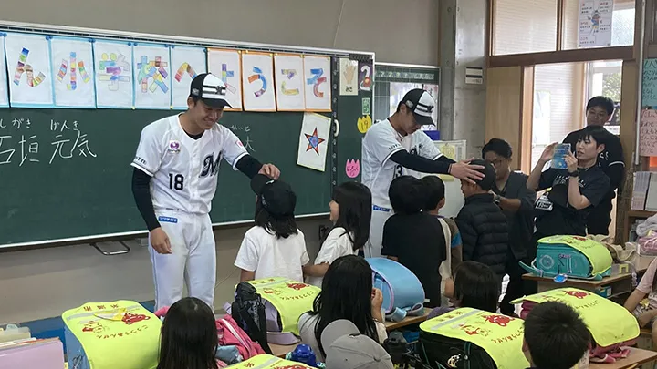 子どもたちと交流する石垣元気投手（手前）と毛利海大投手（奥）【写真：球団提供】